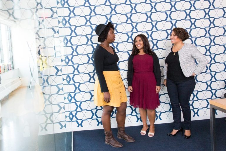 three standing women talking to each other