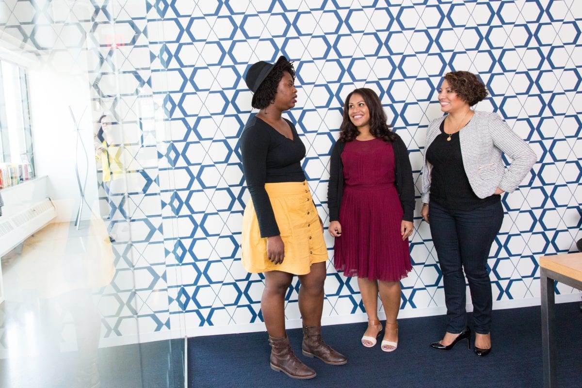 three standing women talking to each other